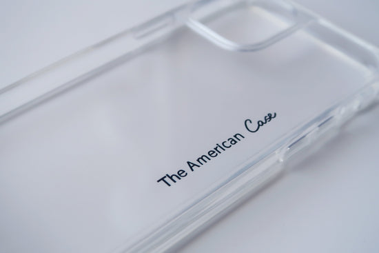 A close-up view of a clear silicon phone case with The American Case logo. The case features precise cutouts for buttons, speakers, and camera lenses, allowing full access to the phone's features.