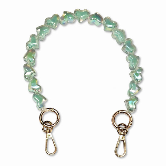 A short bead chain with golden carabiners and a glittery heart charm in light blue color. The chain is designed to be attached to a phone case and can be worn around the wrist for a playful and eye-catching look. The chain is made by The American Case and is designed to be durable.