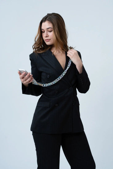 A lady wearing a crystal-effect resin  phone chain with gold buckle details. The chain can be worn across the body for hands-free convenience. The lady smiles and holds the phone with The American Case in her hand.