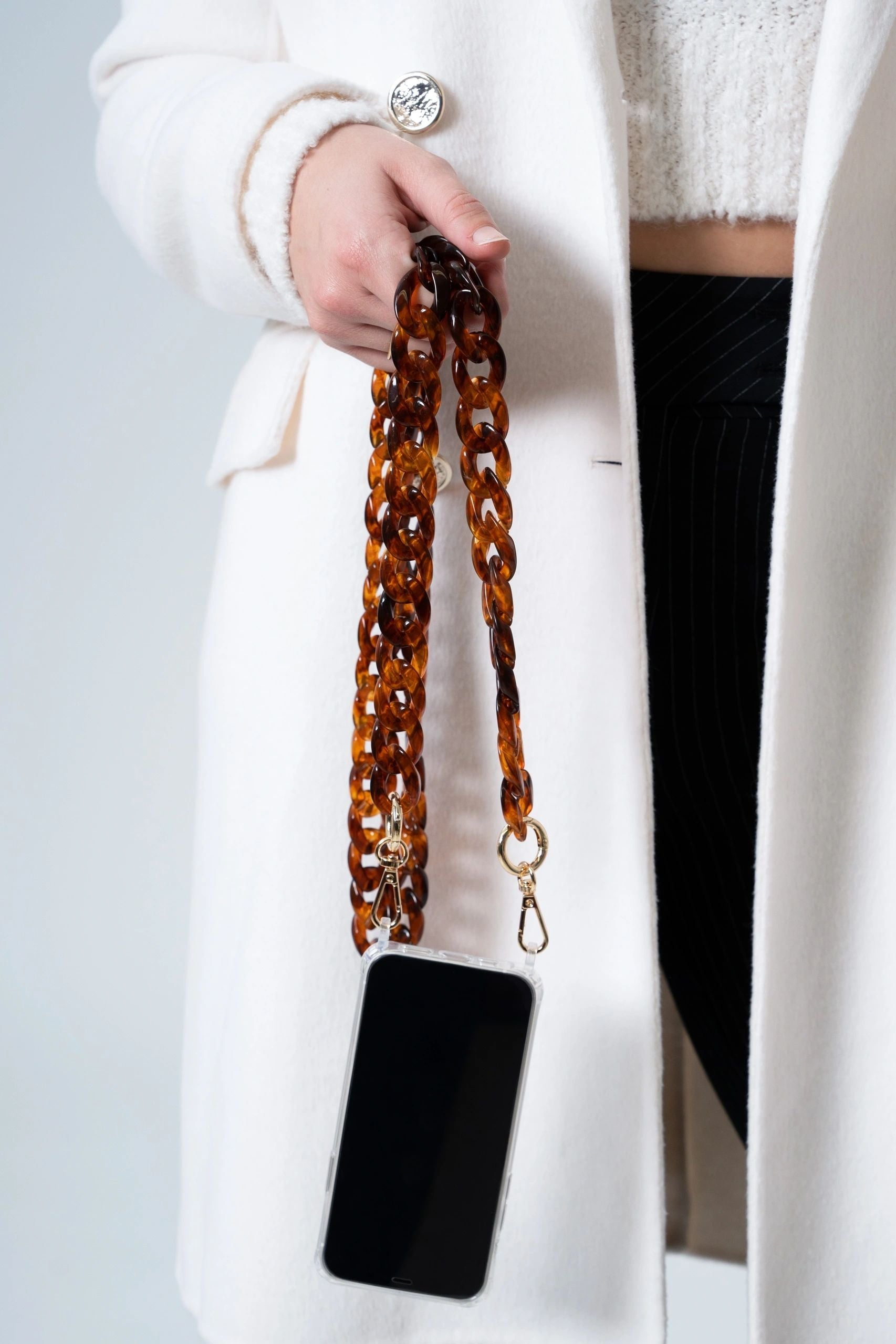 dark Brown Resin link long Chain with Golden Carabiners attached to a phone hold by a lady by her hand