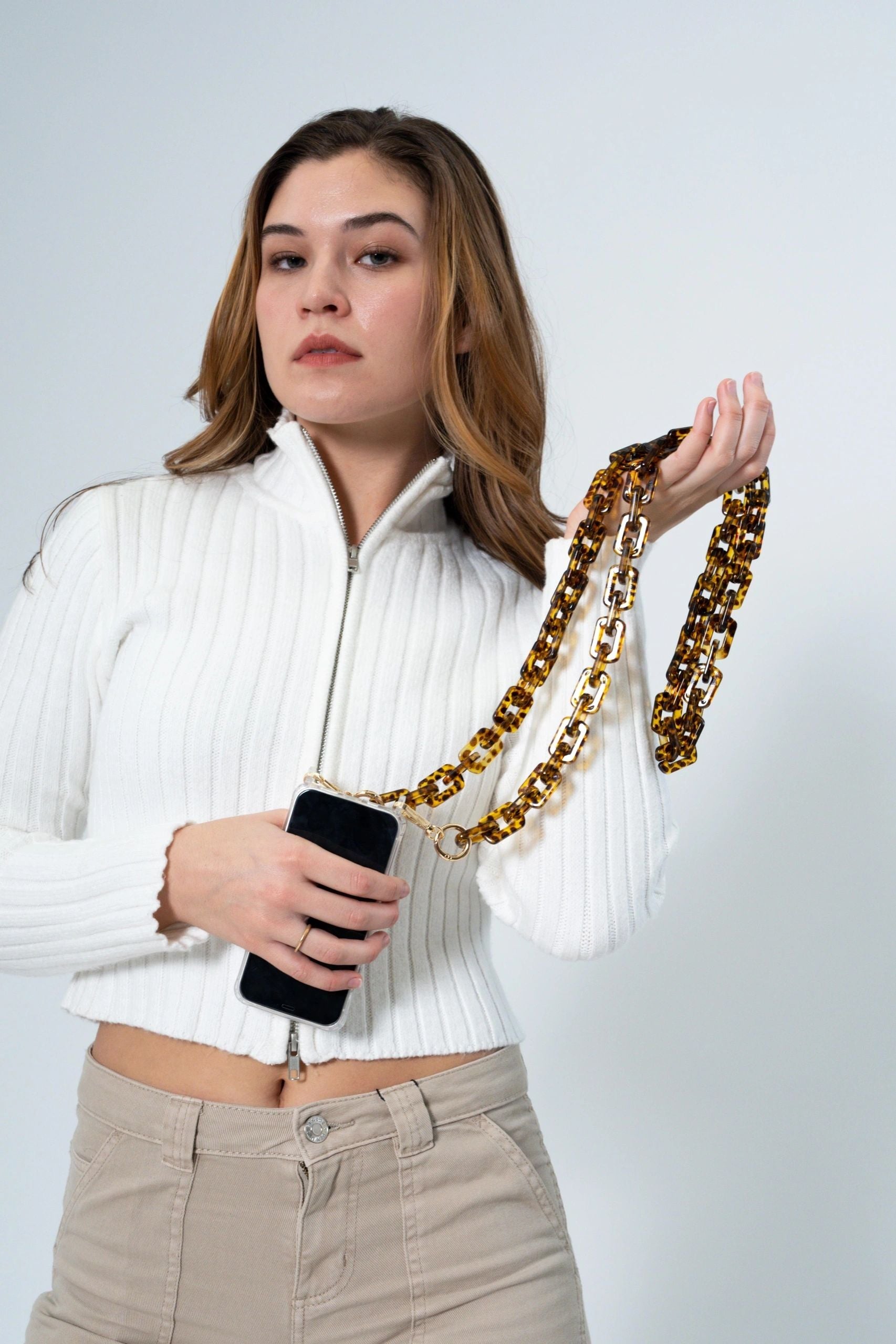 Brown Tortoiseshell Rectangular Resin Chain with Golden Carabiners attached to a phone carried by a lady on her hands
